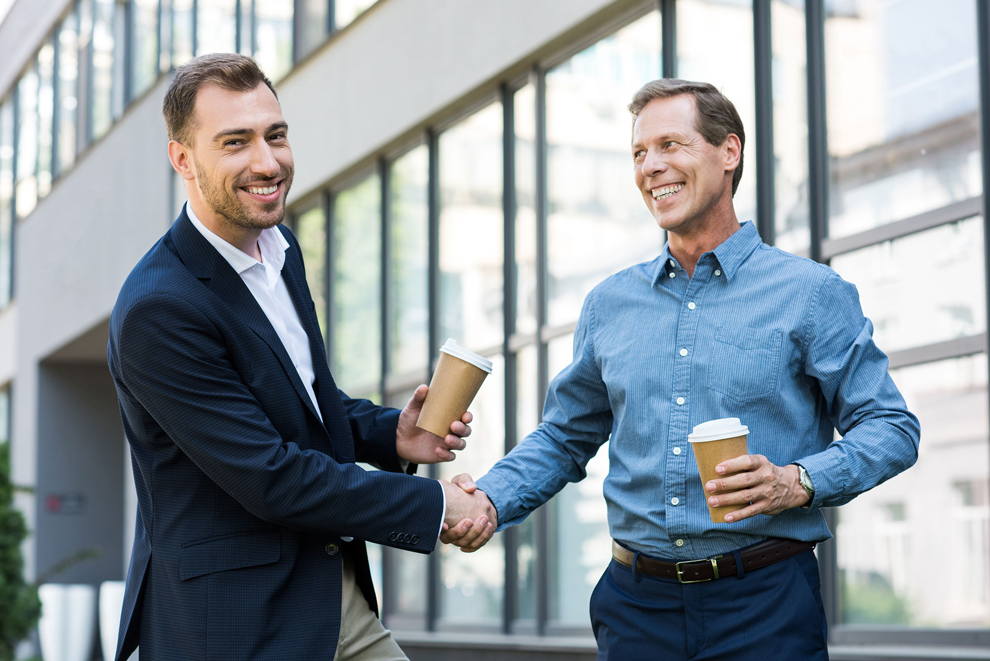 smiling businessmen with disposable cups of coffee